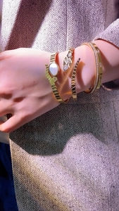 Detail of gold snake bracelet with zircon eyes and shell inlay on business suit