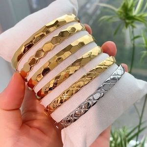 Dettaglio di bracciali geometrici in oro e argento su un cuscino da esposizione bianco