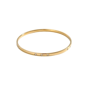 Detailed view of elegant gold bangle with inset white zirconia stones on polished metal
