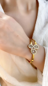 Detail of a gold adjustable bracelet with geometric crystal charms on a model's wrist