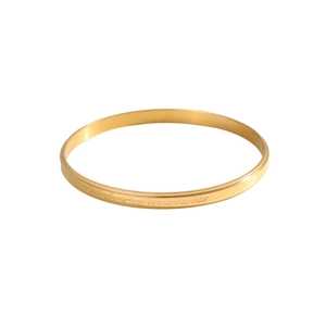 Detail of gold-tone bangle featuring Hakuna Matata engraving and knurled edges
