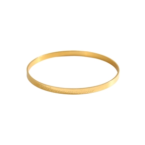 Detailed macro view of gold minimalist bangle featuring engraved Hakuna Matata text