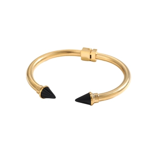 Dettaglio macro del bracciale a cerniera dorato con borchie nere a punta e finitura