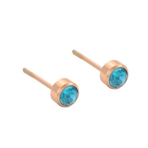 Détail de boucles d'oreilles rondes en or rose serties de cristaux bleus sur fond blanc