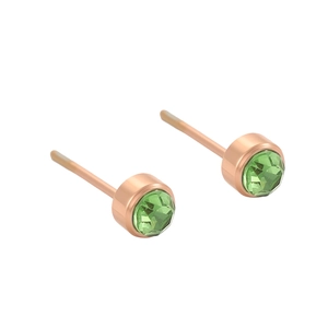 Gros plan de petites boucles d'oreilles rondes en or rose avec zircons verts