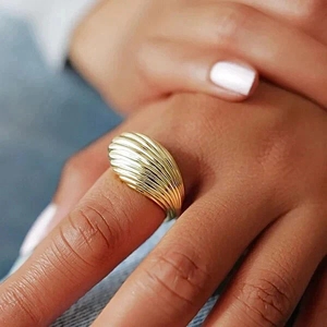 Detailed view of a gold-plated dome ring featuring vertical textured stripes on model's hand