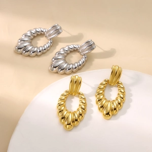 Detail of twisted spiral oval earrings in polished gold and silver finishes