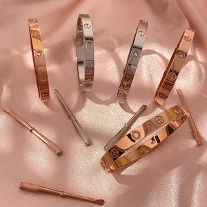 Gestapeltes Armreif-Set in Silber und Roségold mit Schraubmotiven und Kristallen auf Satin