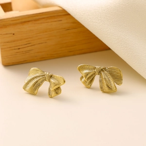 Macro detail of golden bow earrings featuring a delicate striped crinkle texture finish