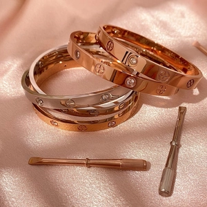 Makroaufnahme von Armreifen mit Schraubmotiv in Roségold und Silber mit Mini-Schraubendrehern