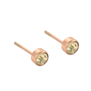 Détail de boucles d'oreilles rondes en or rose serties d'une pierre jaune facettée