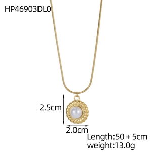 Détail du pendentif doré avec perle blanche et bordure torsadée sur chaîne serpent