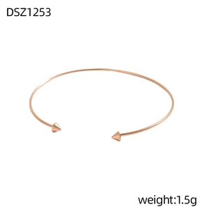 Detail eines roségoldenen Armreifs mit eleganten, konischen Enden und minimalistischem Design