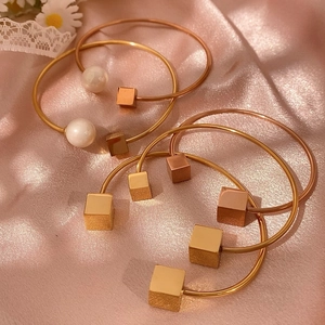 Bracciali aperti regolabili geometrici oro e oro rosa con perle su sfondo di raso rosa