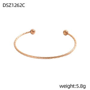 Makroaufnahme des roségoldenen Armreifs mit geometrischer Textur und glatten Metallperlen