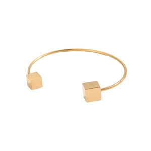 Dettaglio del bracciale rigido dorato geometrico con estremità a cubo su sfondo bianco