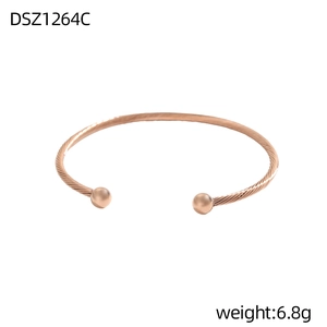 Detailansicht eines roségoldenen gedrehten Armreifs mit glatten Metallkugel-Endstücken