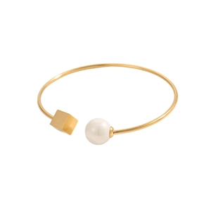 Dettaglio del bracciale rigido dorato con cubo geometrico e perla bianca raffinata