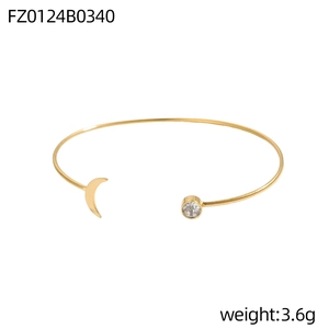 Makroaufnahme eines goldenen C-Armreifs mit Sichel-Detail und glänzender Zirkonia