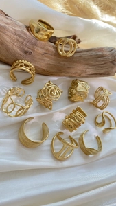 Detailed view of vintage gold hollow rose and textured rings on elegant white satin and wood