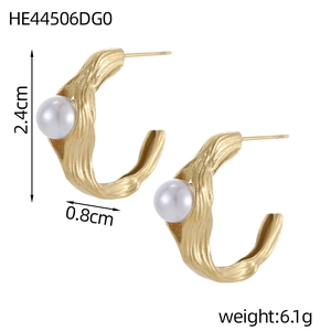 Close-up of vintage C-shape gold earrings with irregular texture and white pearls