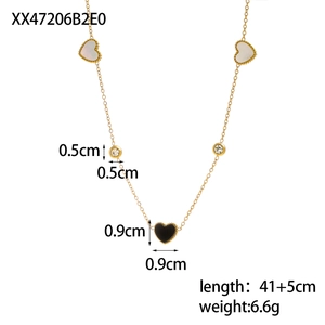 Detail of gold chain necklace featuring black heart and white mother of pearl pendants