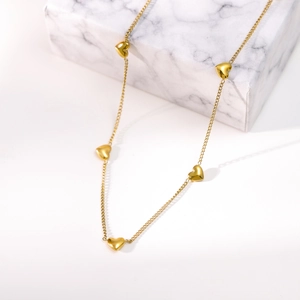 Elegant gold necklace with five 3D heart pendants displayed on a marble block