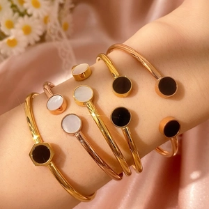 Dettaglio di bracciali rigidi geometrici sovrapposti in oro e oro rosa con intarsi