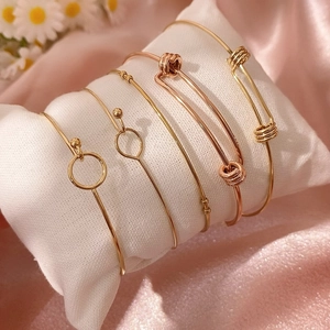 Vista dettagliata di cinque braccialetti con perline oro e oro rosa su cuscino bianco