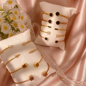 Eleganti bracciali aperti placcati oro con motivi geometrici su raso rosa chic