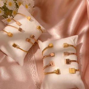 Bracciale rigido geometrico minimalista con cubi su cuscino per gioielli e sfondo satin