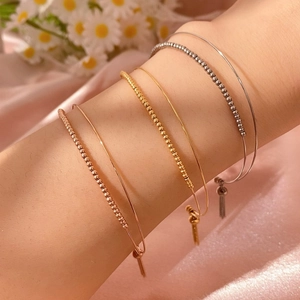 Vista dettagliata di tre braccialetti minimalisti con perline in oro rosa, oro e argento