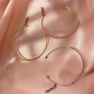 Set di tre bracciali aperti con perline in oro, oro rosa e argento con nappe in metallo