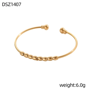 Dettaglio macro del bracciale rigido dorato minimalista con perline e superficie lucida