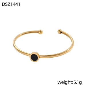 Dettaglio di un bracciale aperto dorato con inserto esagonale nero e punte sferiche