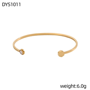 Dettaglio del bracciale aperto dorato con zircone rotondo ed estremità esagonale