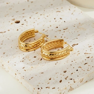 Detail of gold hoop earrings featuring triple-layered design with wheat grain textures