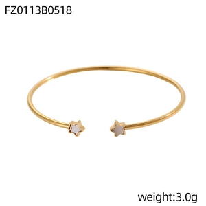 Dettaglio di un bracciale rigido dorato aperto con inserti di stelle in madreperla