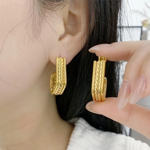 Detail of gold hoop earrings with textured wheat spike pattern and C-shape design
