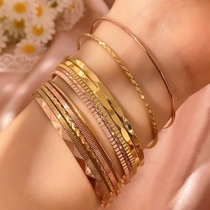 Elegante goud en roségoud gestapelde armbanden met visgraatpatroon en gedraaid design