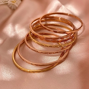 Elegante armbandenset in goud en roségoud met diamantgeslepen textuur op roze zijde