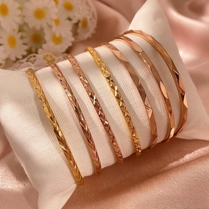 Gele en roségouden metalen armbanden met geometrische gravures op een kussentje