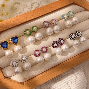 Detalle de pendientes de flores de cristal coloridas con perlas blancas en caja de joyas
