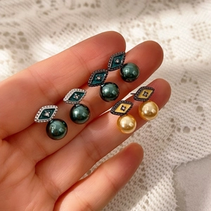 Detalle de los pendientes de rombo con nácar, esmalte de colores y perlas geométricas