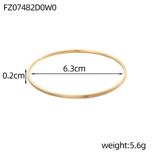Detail van een slanke gouden armband met diagonale textuur, 6,3 cm diameter en 0,2 cm breed