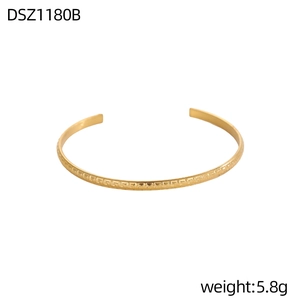 Primer plano de un brazalete dorado con patrón de greca vintage y textura ondulada