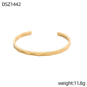 Detalle de la textura geométrica facetada en un brazalete abierto con acabado dorado