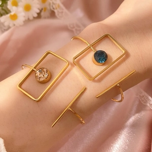 Tres pulseras doradas geométricas con cristales y barra pulida lucidas en la muñeca