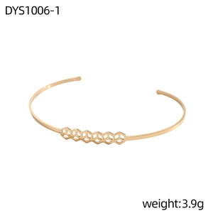 Primer plano de brazalete dorado abierto con estructura geométrica de nido de abeja