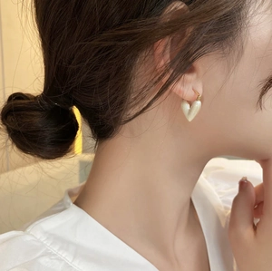 Eleganti orecchini a cuore con ciondoli bianco perla e ganci dorati indossati da una modella